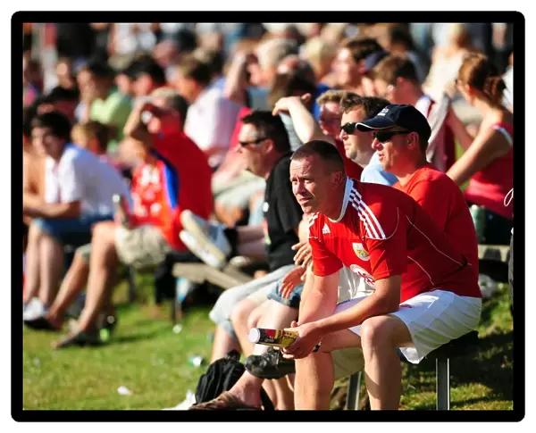 Fans from both teams sit in the sun to watch the game