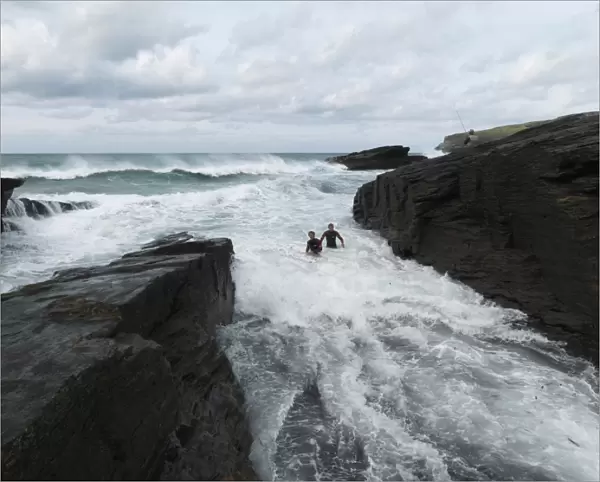 Reconstruction of the rescue of a fisherman by two RNLI lifeguards Chris Boundy and John Dugard at Trebarwith Strand, Cornwall. Picture shows the two lifeguards struggling through surf in the area called the Washing Machine, fisherman on rocks