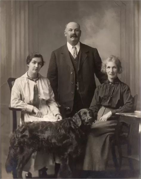 Two women and a man with a Flat-Coated Retriever