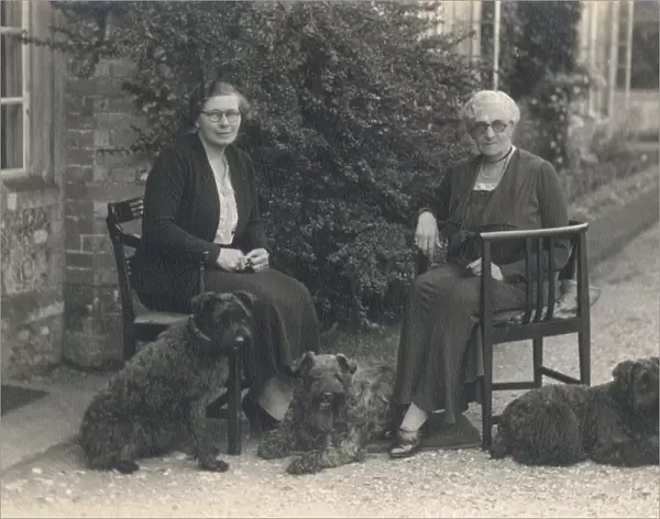 Two women and three dogs in a garden