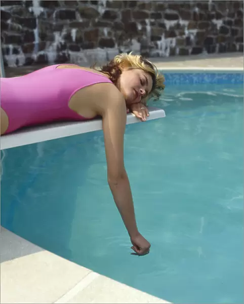 Young woman in pink swimsuit by swimming pool