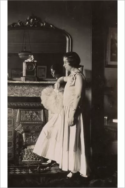 Woman in evening dress standing by a fireplace