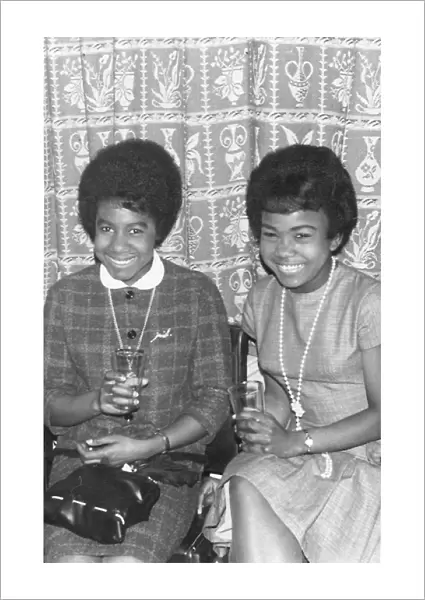 Two British Caribbean ladies in Mod outfits having a drink