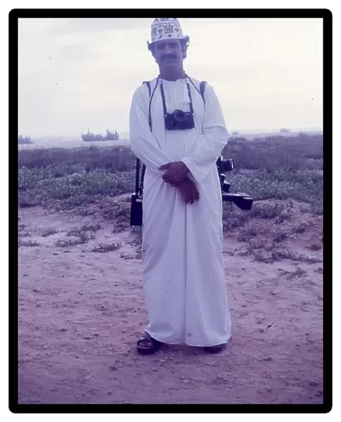 Omani camera man stands on the beach in Salalah Oman