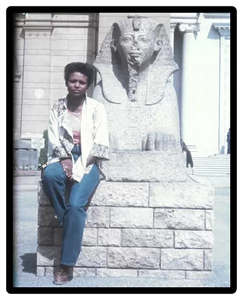Lorna Holder sitting by a Sphinx-like statue - Egyptian Muse