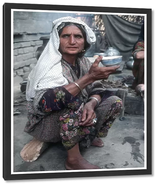 Kashmir - senior woman in traditional dress eats from bowl