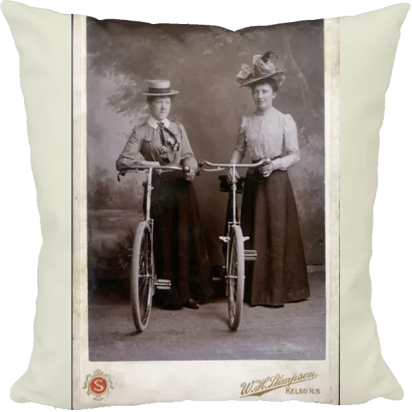 A splendid cabinet photograph of two well-dressed women standing proudly with their bicycles