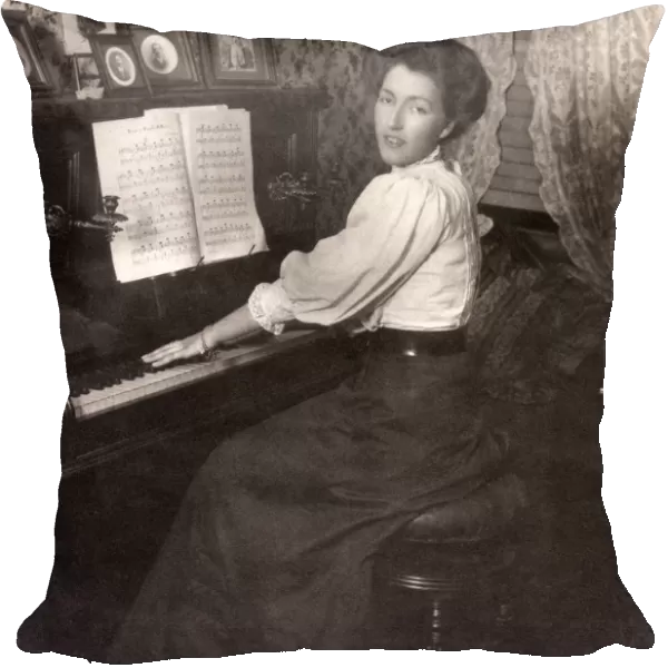 Lady playing an upright piano in her front room