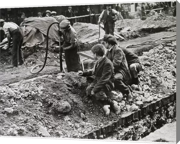Three scruffy boys watch the men digging up the road in Piccadilly