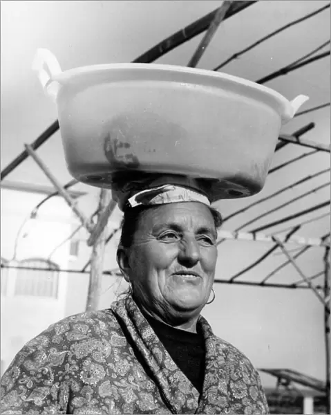 Woman with wet washing on her head, Italy
