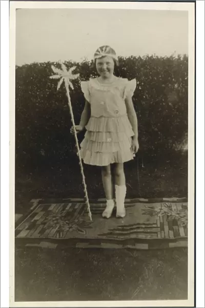 A sweet little girl dressed up in a fairy costume. Shes standing on a rather nice rug in