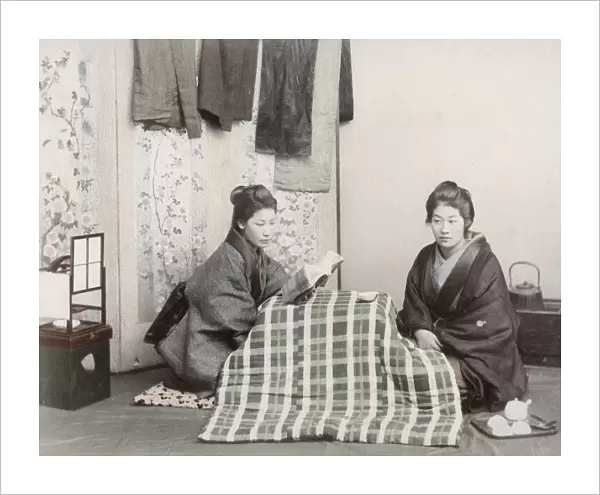 Two young women reading and staying warm, Japan