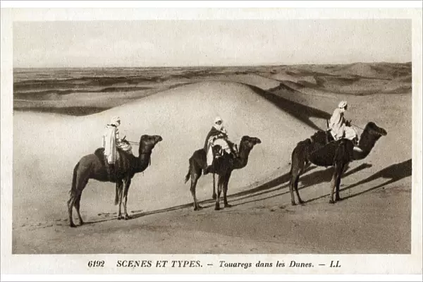Nomadic Tuaregs riding camels amongst the Saharan Dunes - North Africa