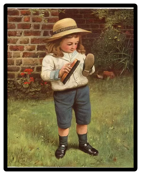 A young boy brushes his shoes. Date: 1910