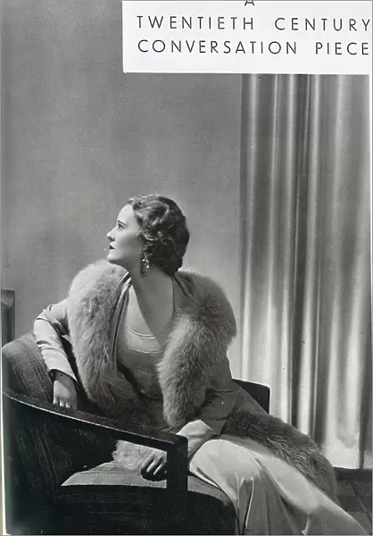 Averil Streatfield (1911-1977) is here seen modelling a crepe romain gown and a coat bordered with grey fox, by designer Norman Hartnell (1901-1979). Date: 1932