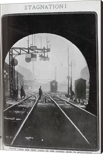 Photograph of rail strike in France, with soldier and striking worker with rifles and bayonets, on railway line by signals, at the exit from a tunnel. Captioned, Stagnation