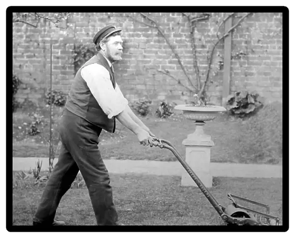 Gardener mowing a lawn with a Thomas Green lawnmower