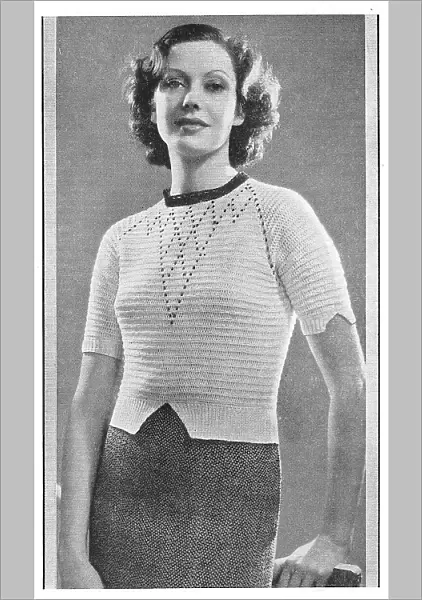 Model wearing a knitted sweater in white Tricoton cotton with shaped sleeve cuffs. Date: 1935