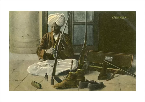Indian Bearer - cleaning his Masters shoes and rifle