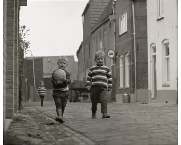 Two boys with a football in the street