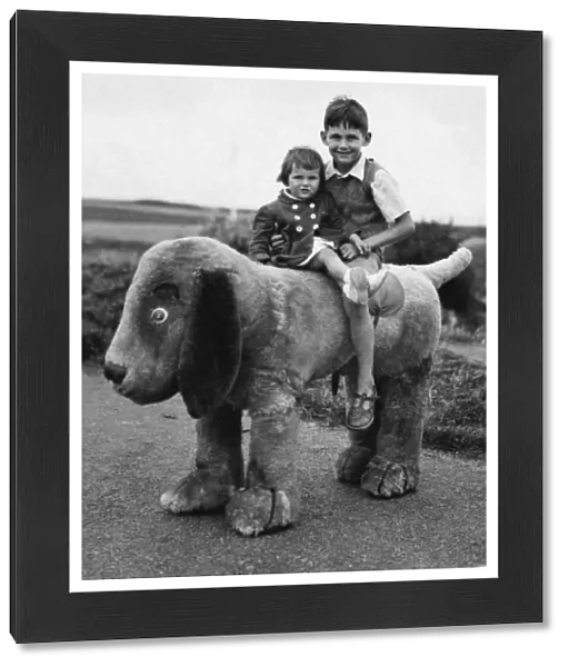 Two children sitting on a large toy dog
