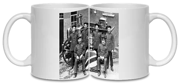 Firefighters pose in front of a steam pump