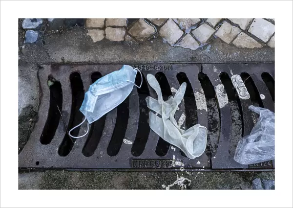 13132595. Mask and surgical gloves on top of urban sewer grid