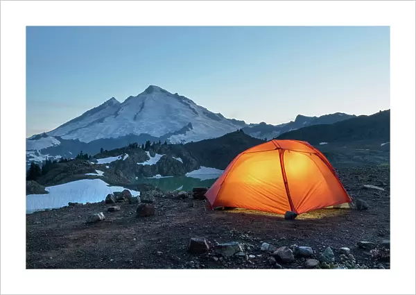 Red Big Agnes backpacking tent illuminated at twilight at backcountry camp on Ptarmigan Ridge. Mount Baker Wilderness. North Cascades, Washington State Date: 24-08-2021