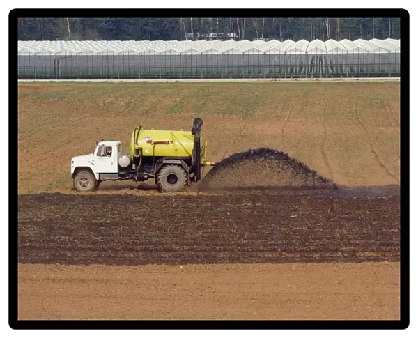 A tractor spreading pig manure on a field