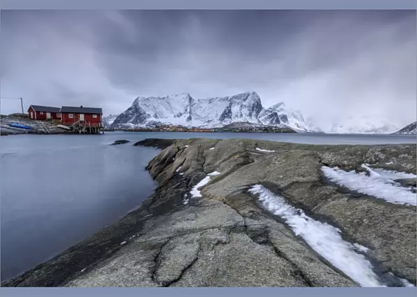 Typical landscape of Hamnoy with red houses of fishermen and the snowy mountains