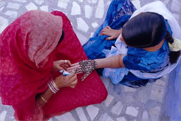 Womans hand being decorated with henna design