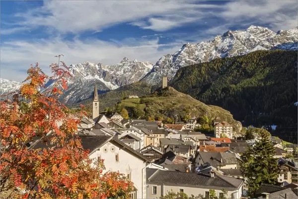 Autumn colors frame the village of Ardez surrounded by woods and snowy peaks, Engadine
