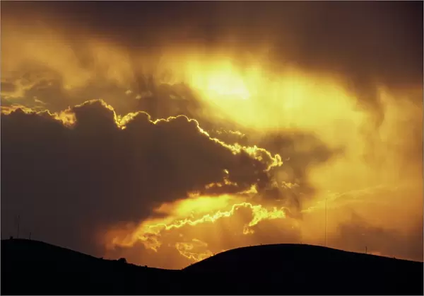 Sun behind dark clouds at sunset over hills at Guanajuato