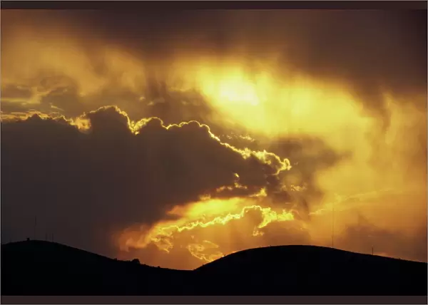 Sun behind dark clouds at sunset over hills at Guanajuato