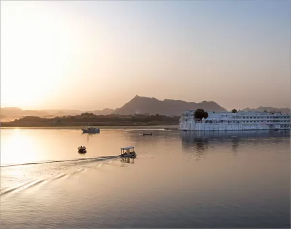 Boat going out to Lake Palace Hotel at dusk, the hotel is situated in the middle of Lake Pichola