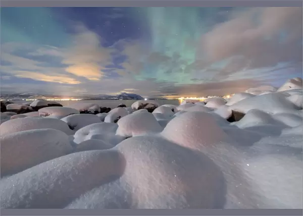 The pink light and the aurora borealis (Northern Lights) illuminate the snowy landscape