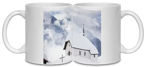 Clouds above the mountain huts and church covered with snow, Bettmeralp, district of Raron