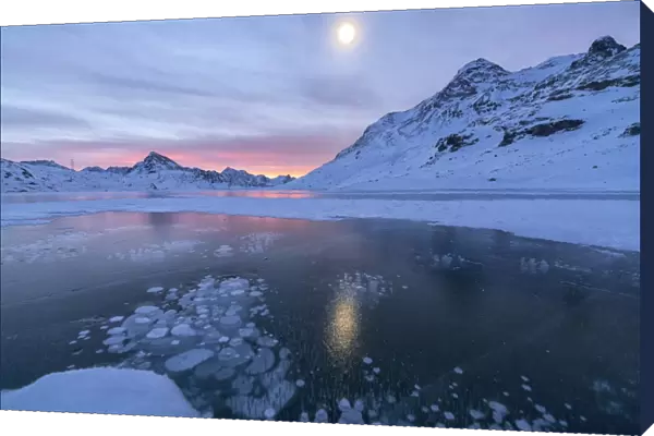 Ice bubbles frame the frozen Lago Bianco at dawn, Bernina Pass, canton of Graubunden