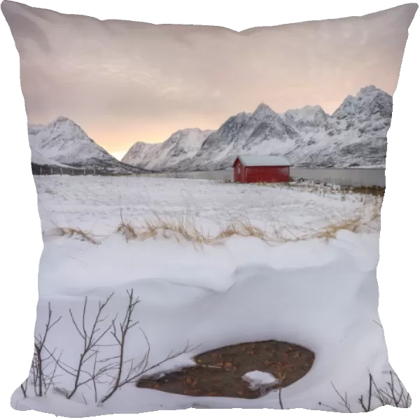 Panorama of pink sky at dawn on the wooden hut surrounded by frozen sea and snowy peaks