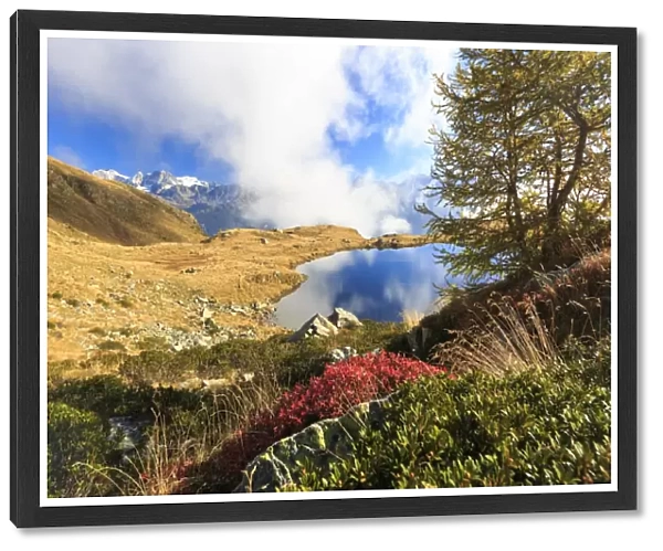 Clouds on peaks of Bernina Group reflected in Lake Arcoglio, Val Torreggio, Malenco Valley