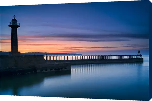 Sunset afterglow over Whitby West Pier and lighthouse, the North Yorkshire coast