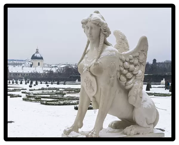 Mythological statue in the snow covered Belvedere Garten, gardens of castle housing