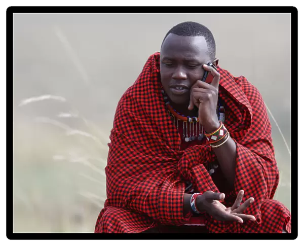 A Masai man talking on a mobile phone in the African savanna, Masai Mara Game Reserve