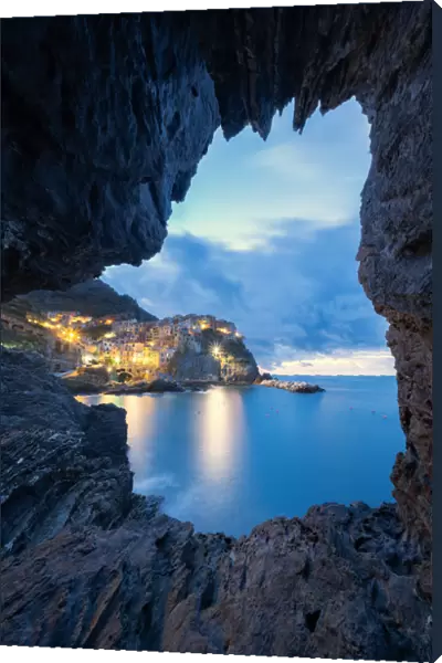 Dusk lights over Manarola seen from a sea cave, Cinque Terre, UNESCO World Heritage Site