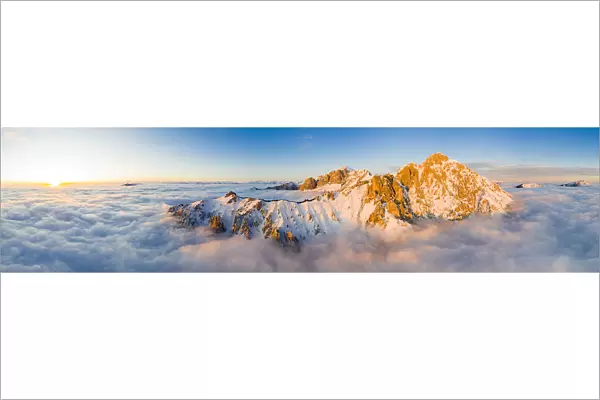 Panoramic aerial view of Grigne group mountain peaks emerging from mist at sunset