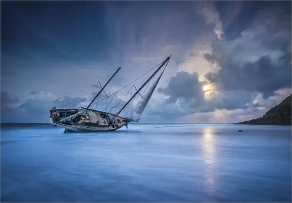 An abandoned sailboat rests on its side at low tide in Moloa a Bay