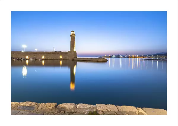 Old lighthouse reflected in the calm sea during the blue hour, Rethymno, Crete island, Greek Islands, Greece, Europe