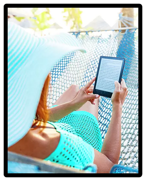 Cheerful woman on a hammock enjoying reading a digital book on tablet, Zanzibar, Tanzania, East Africa, Africa