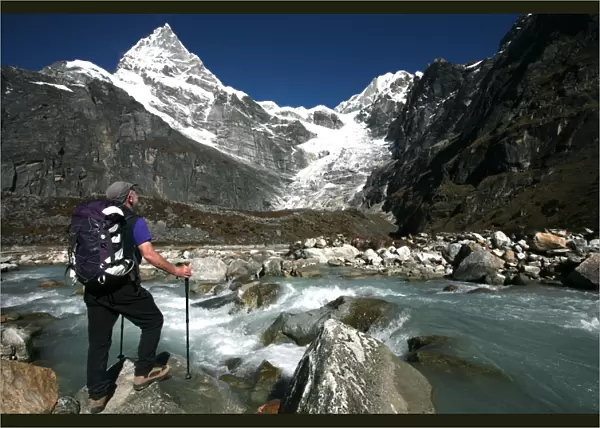 A trekker pauses for a break on the edge of a glacial stream on the way to Mera Peak