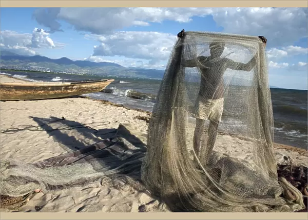 A fisherman tends his nets on Plage des Cocotiers (Coconut Beach) also known as Saga Beach